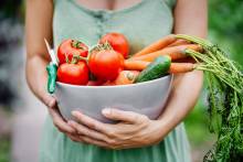 Image of a woman holding a bowl of vegetables. 